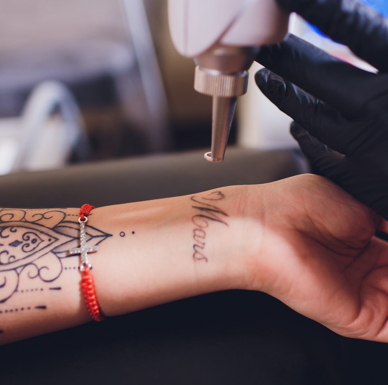 Tattoo artist using a machine on a person's wrist tattoo