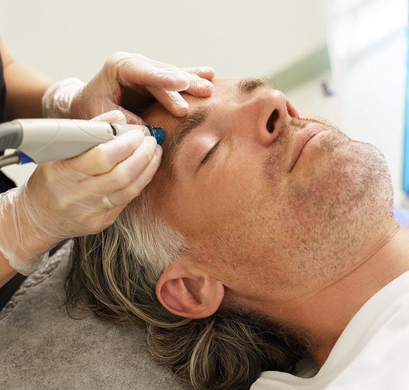 A man receiving a scalp treatment with a handheld device in a spa