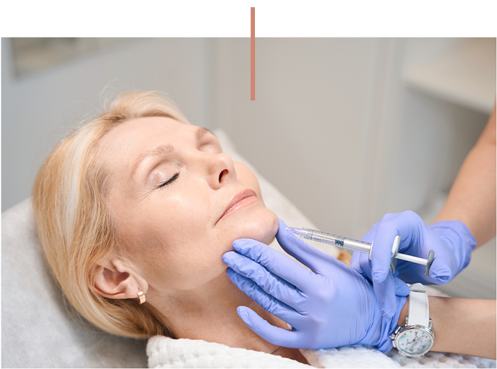 Aesthetic injector giving a woman facial filler injection to the chin