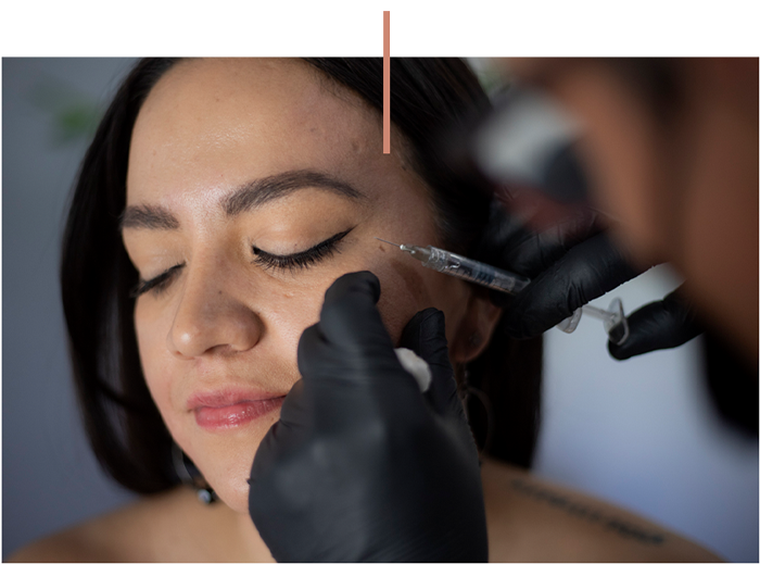 A woman receiving cosmetic facial injection treatment near her cheek