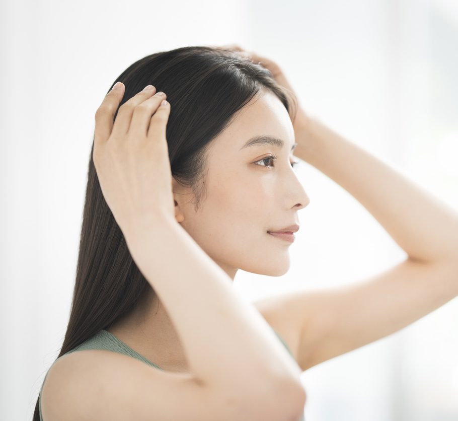 Portrait of a woman adjusting her long black hair against a white background