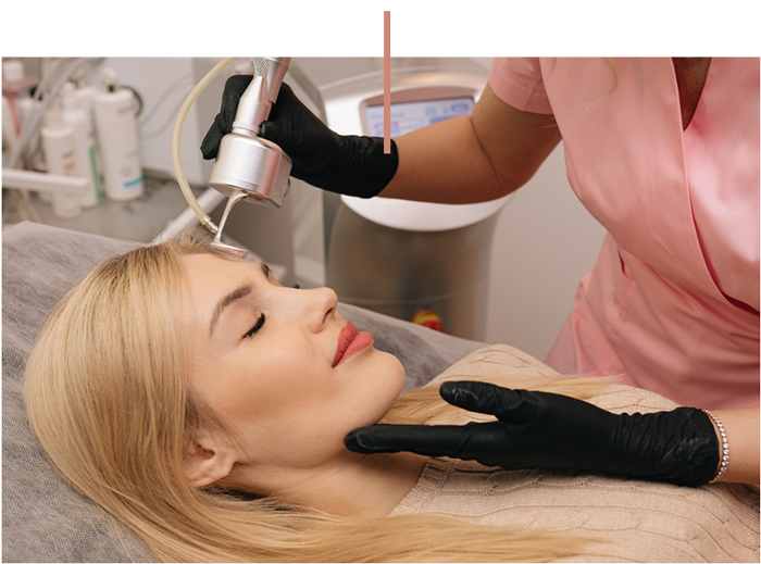Aesthetician performing laser facial treatment on a woman