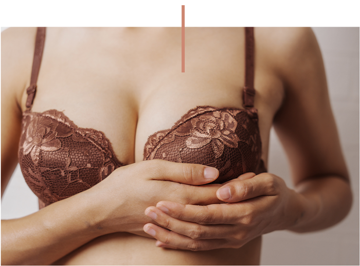 Woman in brown lace bra holding her chest with both hands