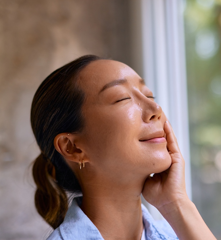 Woman enjoying a relaxing facial massage by a window