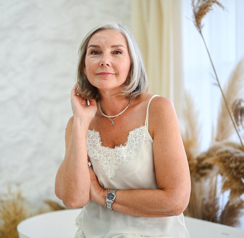 Portrait of a senior woman in a white lace top posing indoors